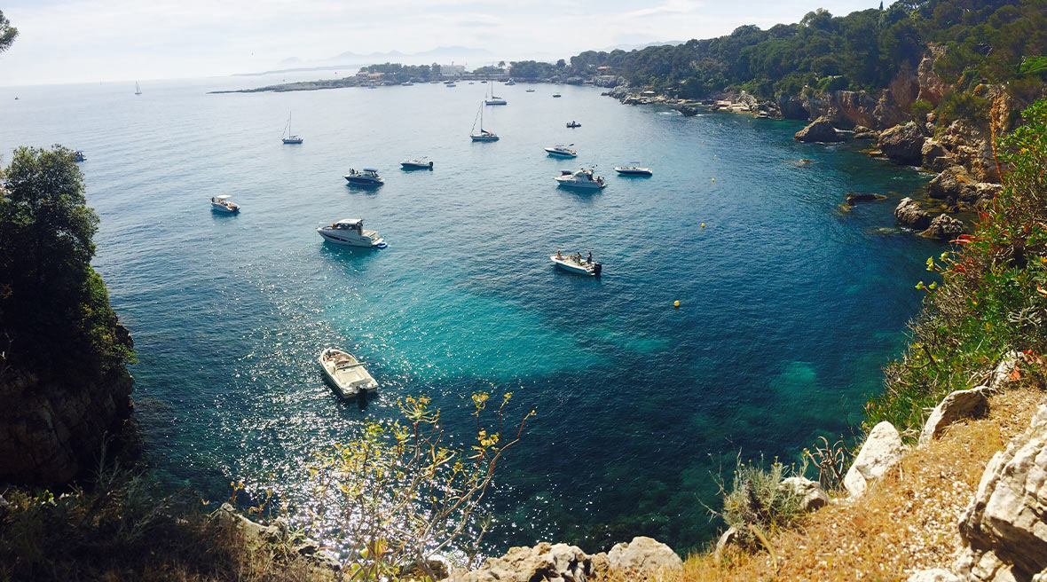 Boats dotted across blue water in a cove off the French coast